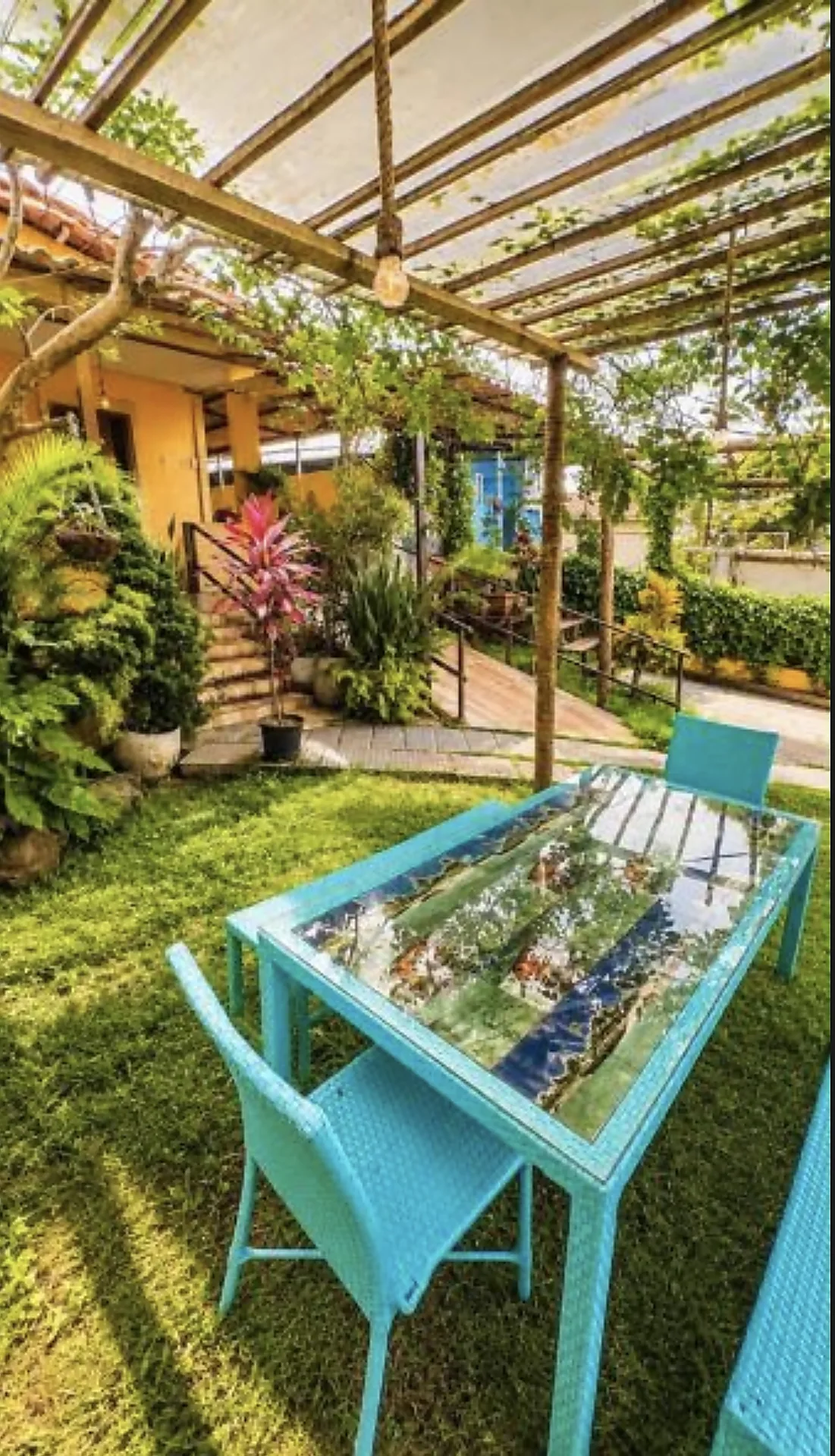 Mesa sob pergolado no jardim da pousada